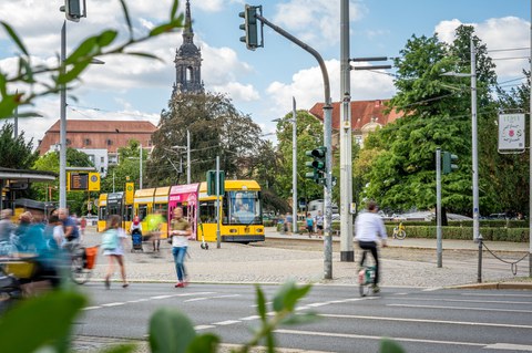 Foto zeigt den Verkehr am Albertplatz in Dresden mit Fußgängern, Fahrradfahrern und der Straßenbahn.
