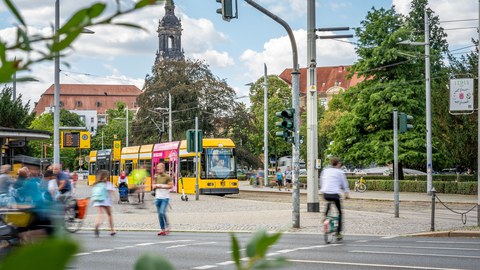 Foto zeigt den Verkehr am Albertplatz in Dresden mit Fußgängern, Fahrradfahrern und der Straßenbahn.