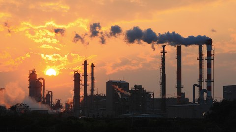 oto eines qualmenden Kohlekraftwerkgebiets bei Sonnenuntergang.