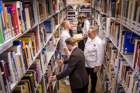 Erich Schwingshackl, Andreas Rieger, Christian Bau, and Nils Henkel browse the shelves. 