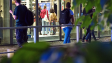 Foto eines TUD-Gebäudes, durch dessen Glasfassade eine kleine Menschengruppe erkennbar ist.