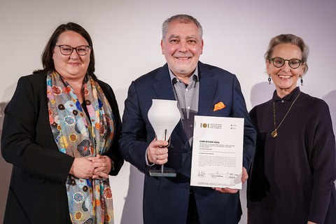 Katrin Stump (left) and Prof. Ursula Staudinger (right) present the certificate and vessel statuette to top chef Christian Bau.