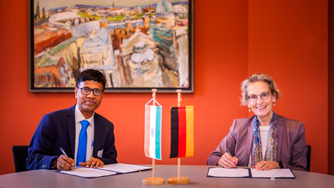 Foto von zwei Personen, TUD-Rektorin Prof. Ursula Staudinger und Dr. M. Srinivas (Direktor des AIIMS New Delhi), die ein Dokument unterzeichnen. Im Vordergrund kleine Aufsteller mit einer deutschen und einer indischen Flagge.