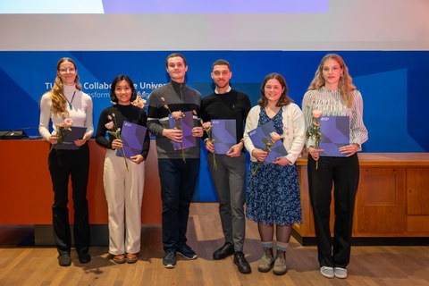 Gruppenfoto von sechs Stipendiatinnen und Stipendiaten des Deutschlandstipendiums mit Blümchen und Urkunden in der Hand.