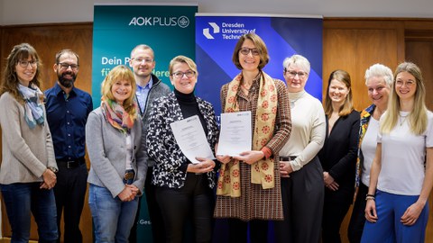 Vertreteri:innen der beteiligten Teams von AOK PLUS und TUD mit den unterzeichneten Vereinbarungen. 