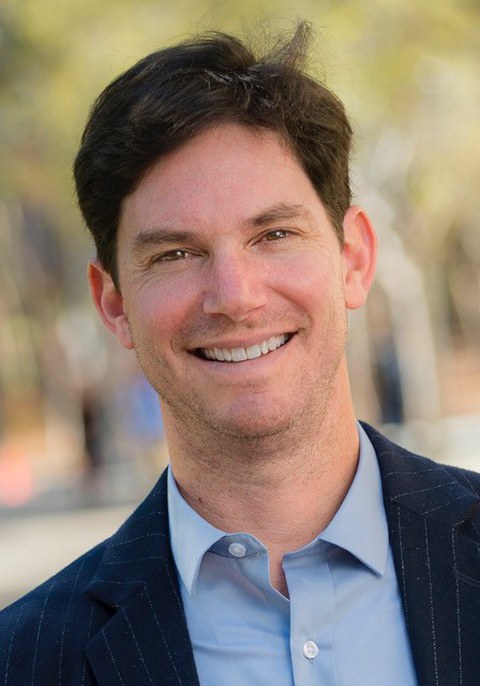 Das Bild ist ein Portrait von Prof. Seth Cohen, mit verschwommenem Hintergrund.