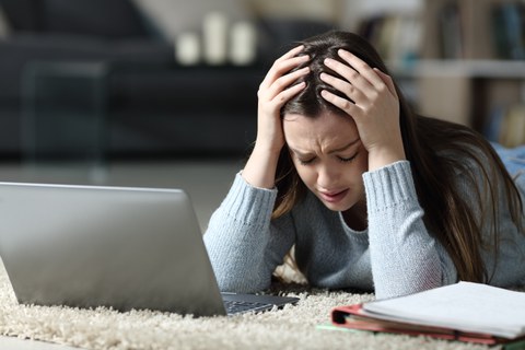 Frau sitzt traurig vor Laptop