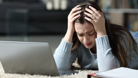 Frau sitzt traurig vor Laptop