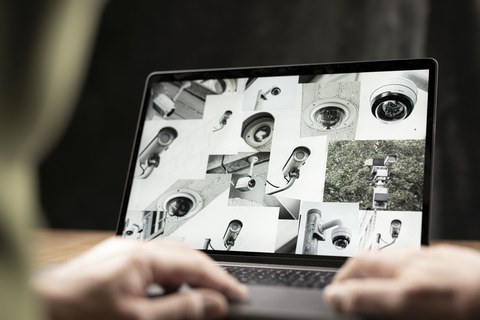 Aufgeklappter Laptop mit einer Collage aus Bildern von Überwachungskameras