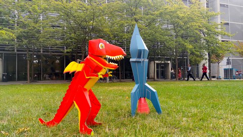 A cardboard dragon and rocket stand before the Auditorium Center.