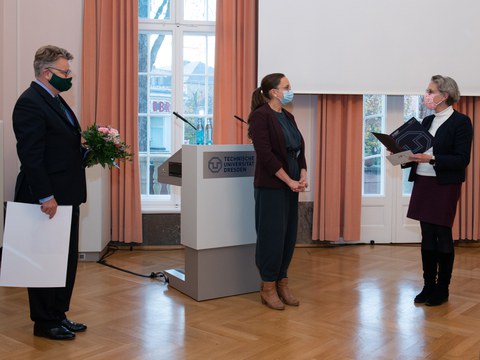 Drei Personen bei der Übergabe eines Preises.