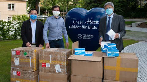 TUD-Rektor Prof. Hans Müller-Steinhagen (r.) nimmt 20.000 Mund-Nasen-Schutzmasken von Prof. Dr. Xinliang Feng (l.) und Dr. Martin Lohe (Sixonia Tech GmbH) in Empfang.