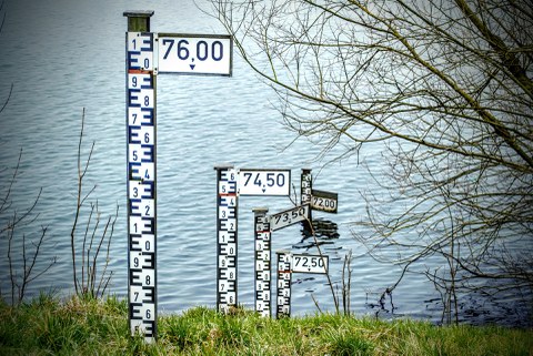 Wasserstandsmesser stehen auf einer Wiese vor einem Gewässer