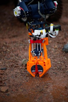 Orangefarbene Greifzange am Marsrover.