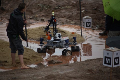 Mars-Rover auf einem Parcour aus Sand und Wasser.