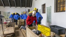 Personen in Schutzkleidung in einem Raum mit Loren.