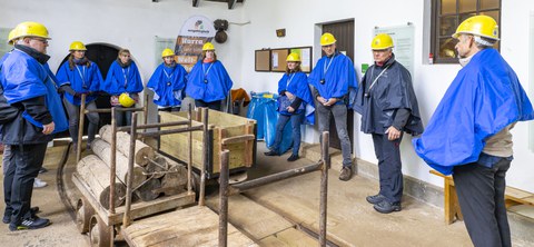 Mehrere Personen in Schutzkleidung umstehen drei Loren.