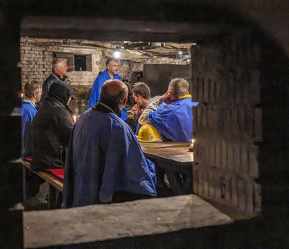 Blick durch eine Öffnung im Mauerwerk auf einen Raum mit Personen in Schutzkleidung.