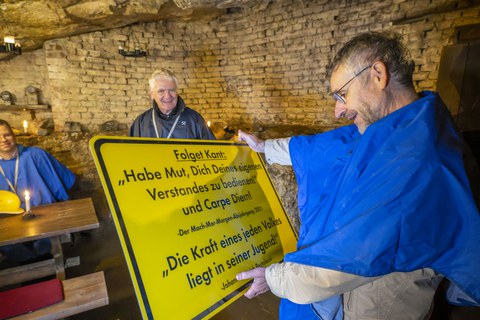 Der Prorektor Bildung hält eine Tafel in der Hand und liest. Auf der Tafel ein Kant-Spruch und das Motto des Abi-Jahrgangs 2001 der Pestalozzi-Schule.