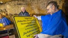 Der Prorektor Bildung hält eine Tafel in der Hand und liest. Auf der Tafel ein Kant-Spruch und das Motto des Abi-Jahrgangs 2001 der Pestalozzi-Schule.