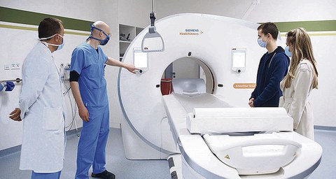 Mitarbeiter zeigen Bewerbern einen Computertomograph.