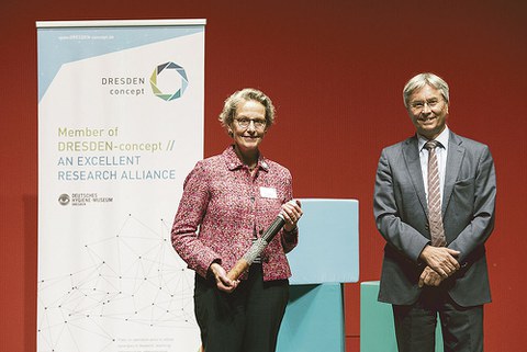 Prof. Ursula M. Staudinger hält den DRESDEN-concept-Staffelstab, den sie von ihrem Vorgänger Prof. Hans Müller-Steinhagen übergeben bekommen hat, in der Hand.