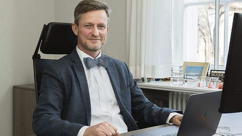Kanzler Dr. Andreas Handschuh sitzt am Schreibtisch.