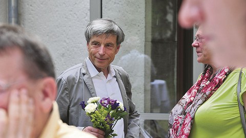 Dr. Lienert, im Gespräch mit einem nicht zu sehenden Gast, hält einen kleinen Blumenstrauß in der Hand.