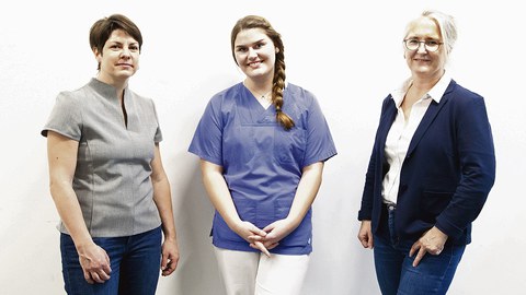 Die drei Frauen stehen nebeneinander vor einer weißen Wand.