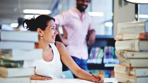 Frau und Mann zwischen Büchern stehend