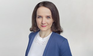 Eine dunkelhaarige Frau mit weißer Bluse und blauem Blazer.