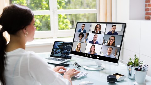 Eine Frau sitzt am PC bei einer Videokonferenz.