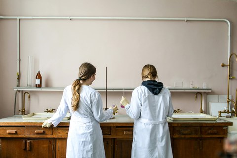 Zwei als Frauen gelesene Personen im Weißen Laborkleid Stehend