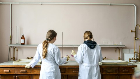 Zwei als Frauen gelesene Personen im Weißen Laborkleid Stehend