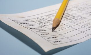 Auf dem Foto ist ein Wochenplan abgebildet. Auf dem Wochenplan liegt ein Bleistift.