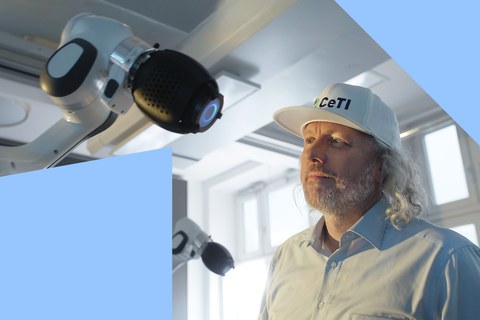 Portrait von Prof. Fitzek mit einem Roboter im Vordergrund