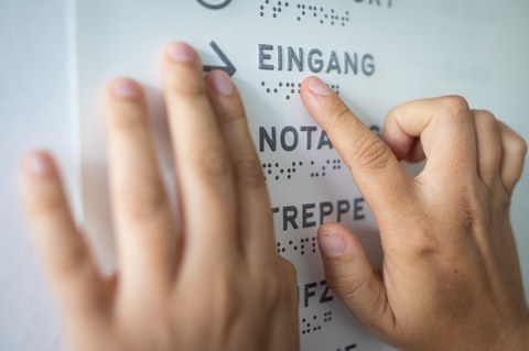 Photo of two hands touching Braille characters on a swell paper.