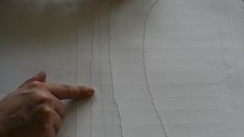 Photo of a tactile printout of a curve diagram. Two hands feel the lines of the graph.