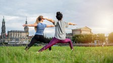 Foto von zwei Personen, die am Elbufer Yoga machen. 