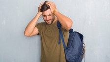 Foto einer Person, die sich mit beiden Händen an den Kopf greift. Das Gesicht der Person ist schmerzverzogen.