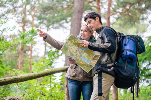 Foto: Zwei Personen wandern und schauen auf eine Wanderkarte.