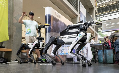 Zwei Roboterhunde und ein Mann mit VR-Brill.