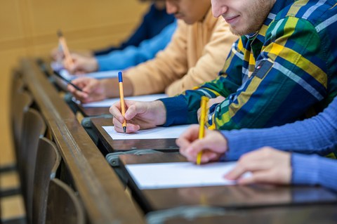 Studenten sitzen im Hörsaal und schreiben Klausur.