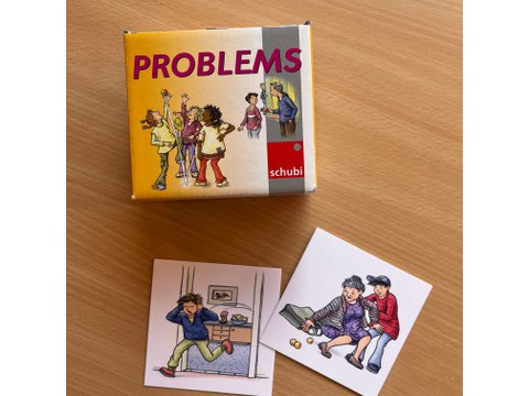  On the table is the “Problems” card set, in front of which are two cards from the set as illustrative examples.