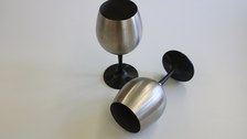 The photo shows the two stainless steel wine glasses, one vessel lies crosswise in front of the upright vessel.