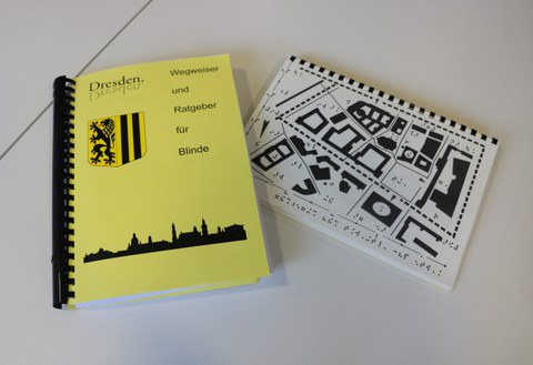 Photograph of the ring binder with explanations of maps of individual city areas in Braille, plus tactile maps in a separate booklet