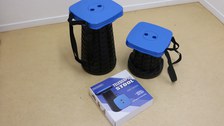 The photo shows two of the telescopic stools from above, they are set at different heights, with the packaging box in front of them.