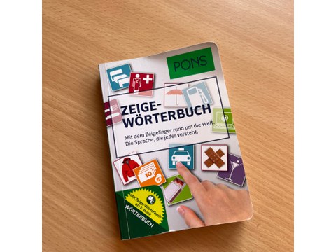 Photographed from above, it shows a copy of the PONS Zeigewörterbuch lying on the table.