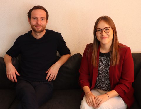 Das Foto zeigt zwei Personen, eine Frau und einen Mann, die zusammen auf einem Sofa sitzen.