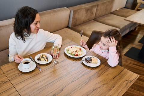 Foto einer Mutter mit ihrer Tochter, die zusammen in einem Restaurant essen. 